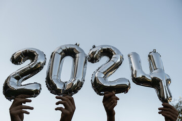 Silver foil number 2024 celebration new year balloon on blue sky background. Happy New year...