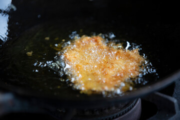 Fried chicken in a sieve on the stove. Selective focus.