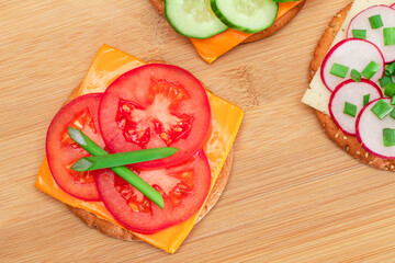 Different Cracker Sandwiches with Tomato, Cucumber, Radish and Cheese on Cutting Board. Easy Breakfast. Diet Food. Quick and Healthy Sandwiches. Crispbread with Tasty Filling. Healthy Dietary Snack