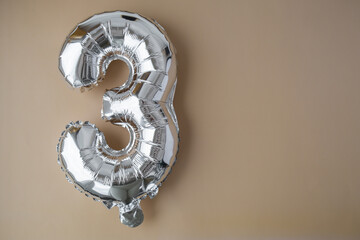 3 three metallic balloon on beige neutral background. Greeting card silver foil balloon number Happy birthday holiday concept. Copy space for text. Celebration party congratulation decoration