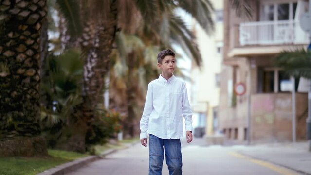 Braving the Storm: Boy in White Shirt Walking Among Palms on a Windy Day