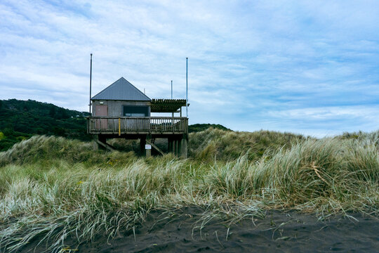 Old lifeguard watchtower on the seashore in cloudy weather, Muriwai beach, New Zealand