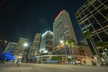 Fototapeta na wymiar Downtown district of of Miami Brickell in Florida, USA. Brightly illuminated high skyscraper buildings and street with car trails and metrorail traffic in modern american midtown