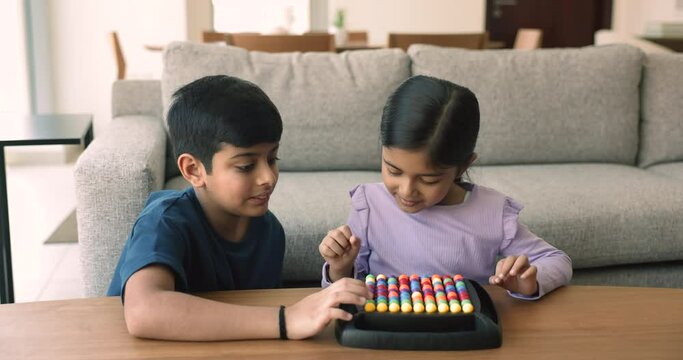 Cute little girl play rainbow balls boardgame with older brother at home. Friendly siblings enjoy IQ board game on leisure in living room. Activity for children cognition, boost concentration, hobby