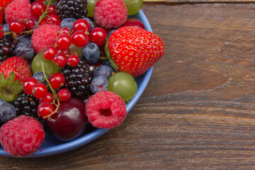 Various summer Fresh berries in a bowl on rustic wooden table. Antioxidants, detox diet, organic fruits. Berries