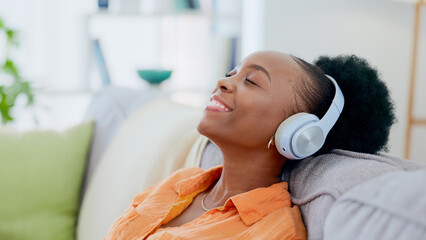 Calm woman, music and headphones in home for listening to audio, radio and hearing podcast on sofa. Happy african person relax for streaming sound, multimedia and peaceful subscription in living room - obrazy, fototapety, plakaty