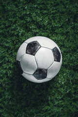 Soccer ball laying on the green grass of soccer field, directly above view