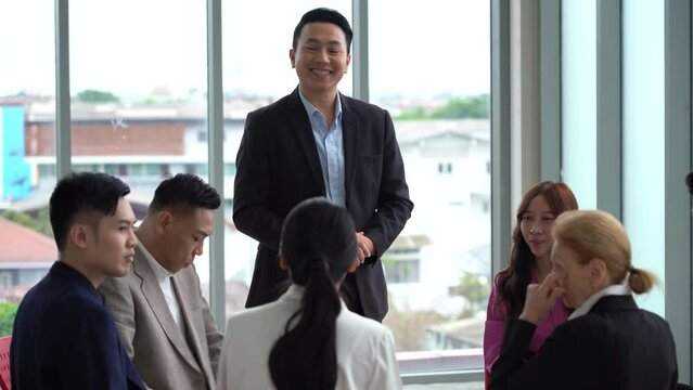 asian business man standing and talking in font of group of diversity business people in circle meeting at  seminar office .