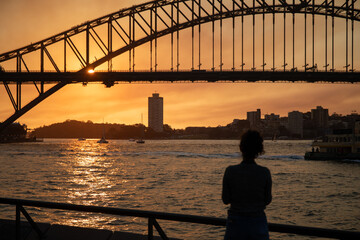 Silhouette of a woman looking at the Sydney Harbour Bridge at sunset