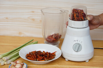 Close up chef hand use blender to blend dried chillies, garlic. lemongrass. Concept, Food ingredient preparation by using electric appliance for convenience in cooking.        