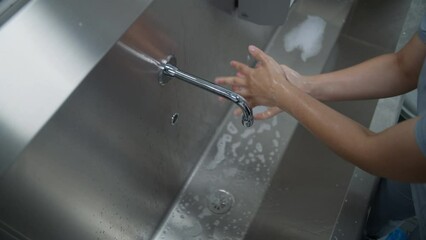 Professional surgeon in uniform cleans hands before surgery. Female medic prepares to performing surgical operation with seriously injured patient. Medical personnel work in modern hospital. Close up. - Powered by Adobe