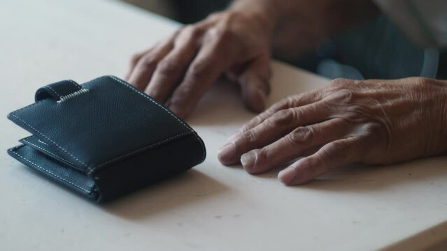 the old man's wallet and hands are on the table. concept bankruptcy, lack of money in old age. financial pension expenses, debt obligations in old age