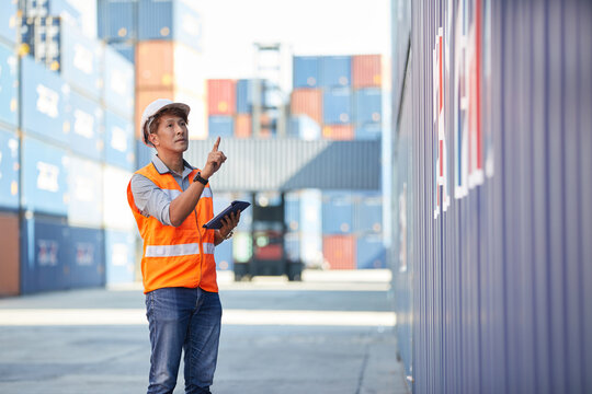 factory worker or engineer looking up and pointing to something in containers warehouse storage