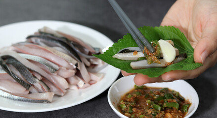 Close-up image of wrapping fresh gizzard sashimi in Sesame leaf.
