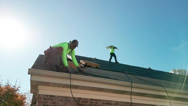Roofer repair or replace shingle that has been damaged and needing replacement at sunny day. Wide footage. Naperville IL. USA. October 28 2022