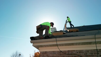 Roofer repair or replace shingle that has been damaged and needing replacement at sunny day. Wide shot. footage. Naperville IL. USA. October 28 2022