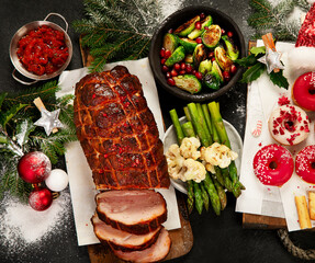 Baked ham with vegetablesand donuts on dark background. Christmas food