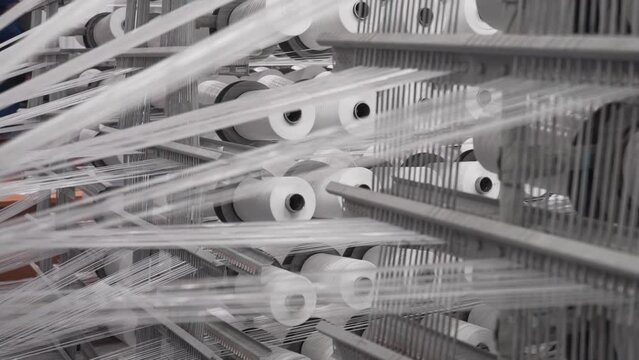 plastic polypropylene flat yarn bobbins loaded on circular weaving loom machine. bobbins with white threads fed to a textile machine
