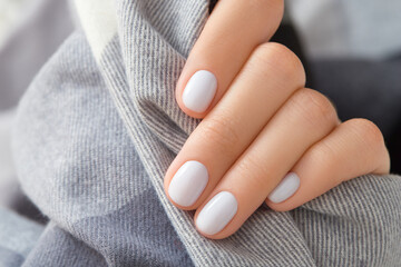Womans hand with white nail design holding fabric