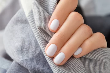 Foto op Aluminium Womans hand with white nail design holding fabric © Darya Lavinskaya