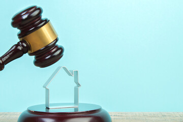 Wooden house, keys and judge's gavel on a wooden table. Symbol of mortgage or dilapidated housing being sold at auction or as symbol of legal dispute over division of real estate.