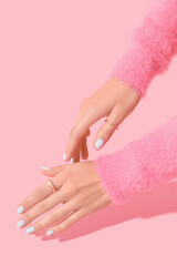 Womans hands with white manicure on pink background