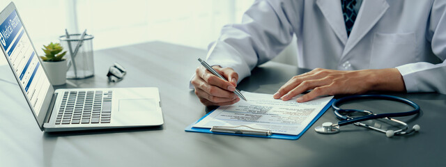 Doctor carefully review detailed medical report on laptop and diagnosing illness for effective...