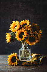 Bouquet of sunflowers in vase against dark background. © Cavan