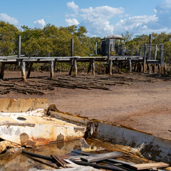 Looking over a wrecked rowboat to a rustic jetty at low tide. Boonooroo, Queensland, Australia. 