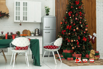 kitchen decorated with pine garlands and Christmas toys. the table and near is worth Christmas tree. interior bright kitchen decorated for Christmas.