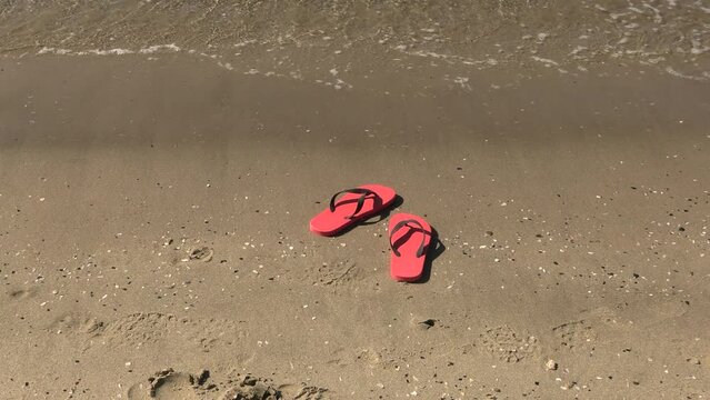 paire de tongs abandonnés sur le rivage d'une plage