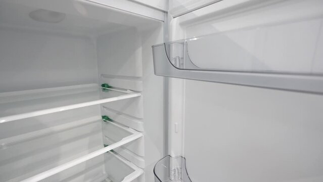 Open empty refrigerator. Refrigerator open empty fridge inside interior. Close up on empty refrigerator with door open. New clean refrigerator. Empty open fridge with shelves. Fridge interior.
