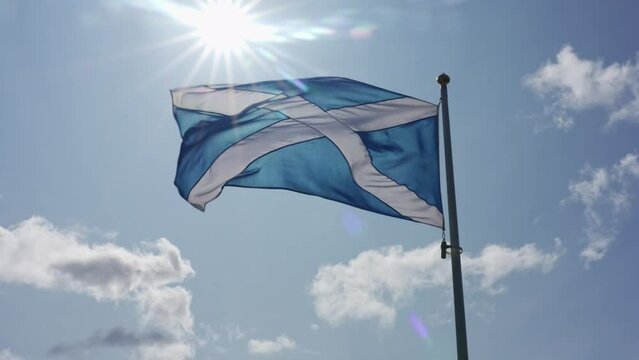 Flag of Scotland moving slowly with the wind on a blue background of the sky.