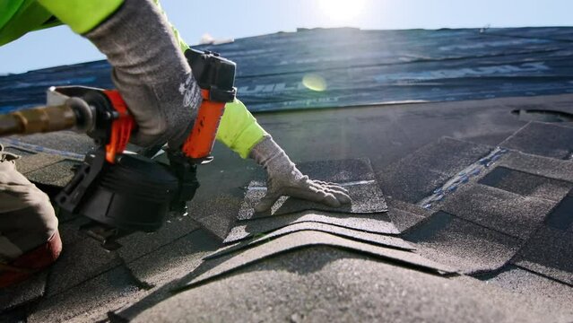 Close up shot of Roofer repair or replace shingle that has been damaged and needing replacement at sunny day. 
