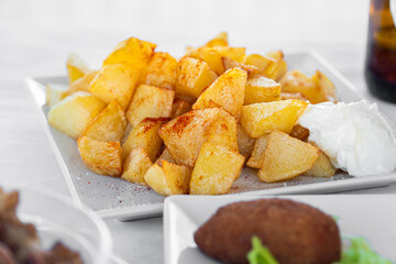Patatas Bravas with mayo on a white plate, spanish tapas.