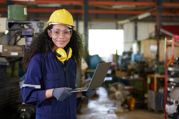 factory worker or technician holding laptop computer in lathe factory
