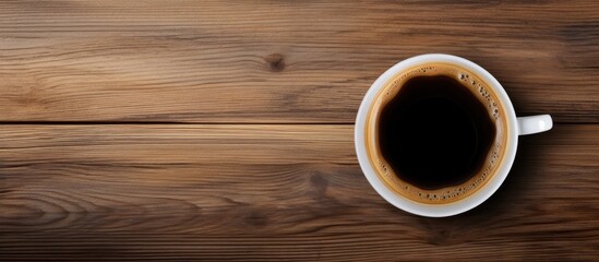 Bird s eye view of a wooden table with a paper cup of black coffee With copyspace for text