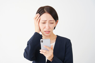 スマートフォンを見て頭を抱えるビジネスウーマン　白背景