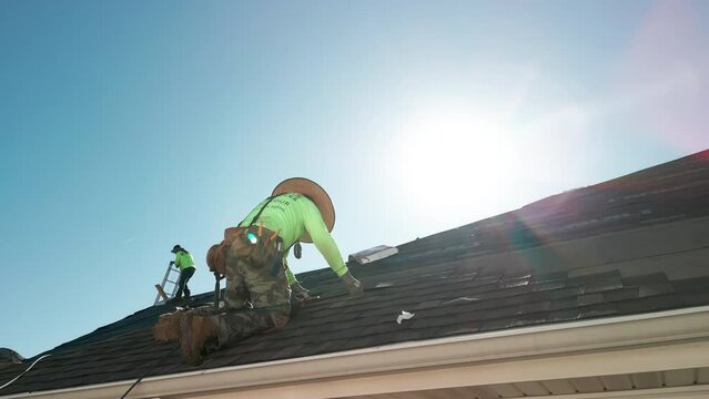 Close up view of Roofer repair or replace shingle that has been damaged and needing replacement at sunny day. 