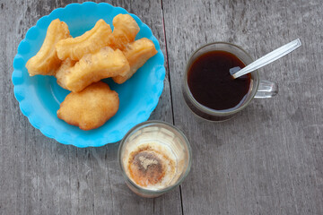 Patongko on a blue plastic plate Black coffee and poached eggs in a glass on a wooden table