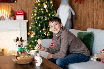 Beautiful blond child, young school boy, playing in a decorated home with knitted toys