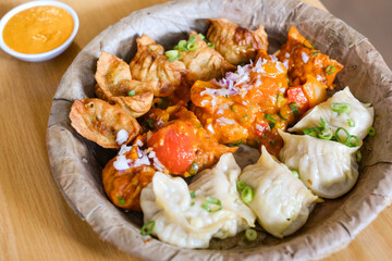 A plate of assorted chicken momos (steamed, fried and chilli sauce dumplings) served on a leaf plate at Tapari Nights, a Nepalese restaurant in Auburn, Sydney - NSW, Australia