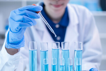Professional scientist chemist technician analysis research experiment virus blue liquid pipette glass test tube equipment in hospital laboratory, woman doctor white lab coat medical research develop
