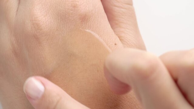 Female hands care. Close up of woman applying serum gel on hand skin. Serum oil with hyaluronic acid applied by a woman's hand, skin care cosmetics, moisturizing gel.