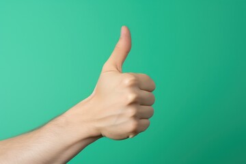 Close-up of a human hand showing thumbs up isolated on green background. Gesturing of trust, agreement, positive green signal, validation, like, and support.