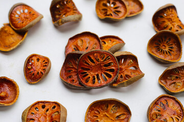 Dried bael fruit slices on white background.