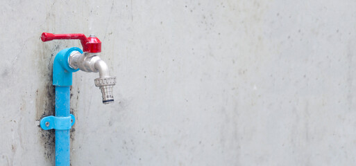 Faucet on cement wall background.