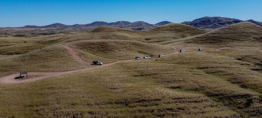 Fototapeta premium Panorama photo of cars driving in the mountains on a dirt road, Namibia, Africa, 