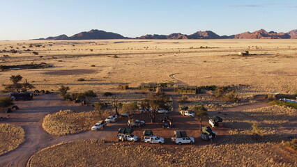 4x4 cars parked on a field in the grass with mountains in the horizon, Namibia, Africa