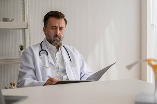 Portrait of professional doctor sitting in uniform with stethoscope in hospital. confidence smart male doctor sitting in medical examination room.